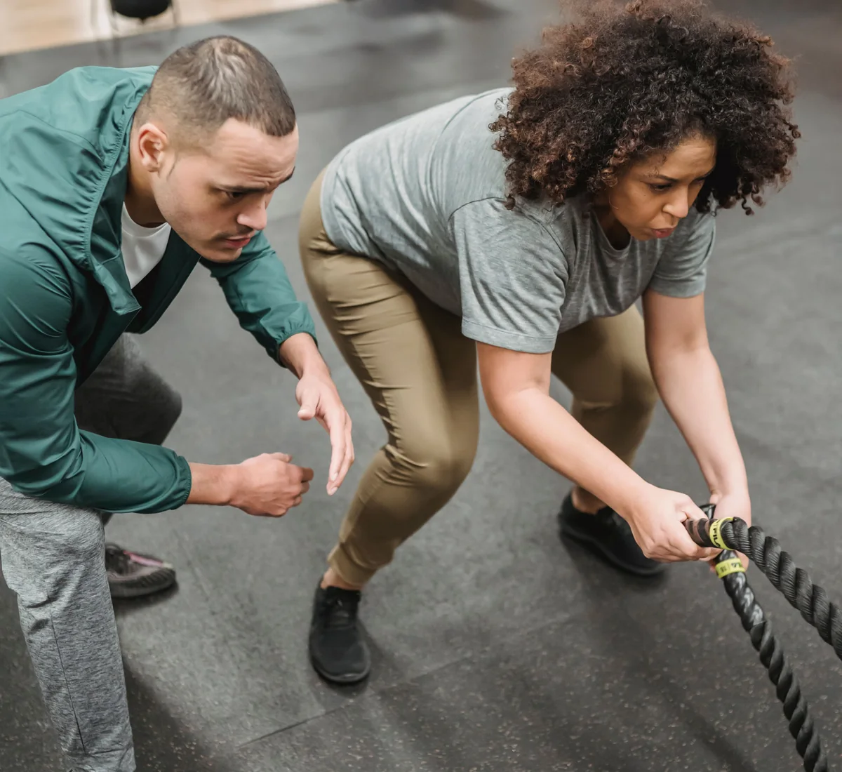 African woman doing a battle-rope workout with a coach