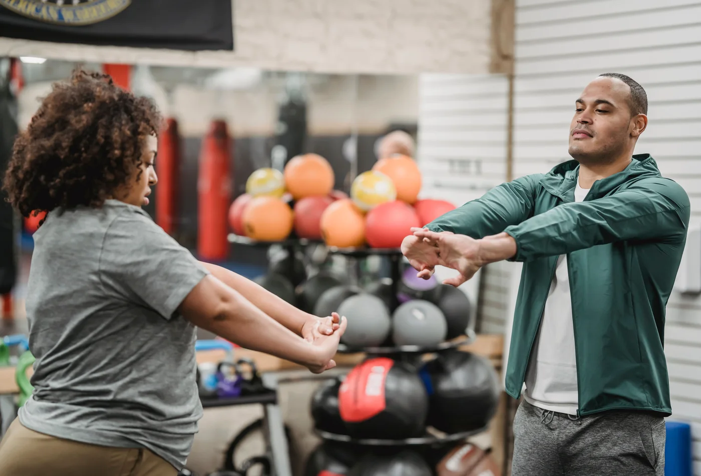 African gym member warming up with a fitness coach